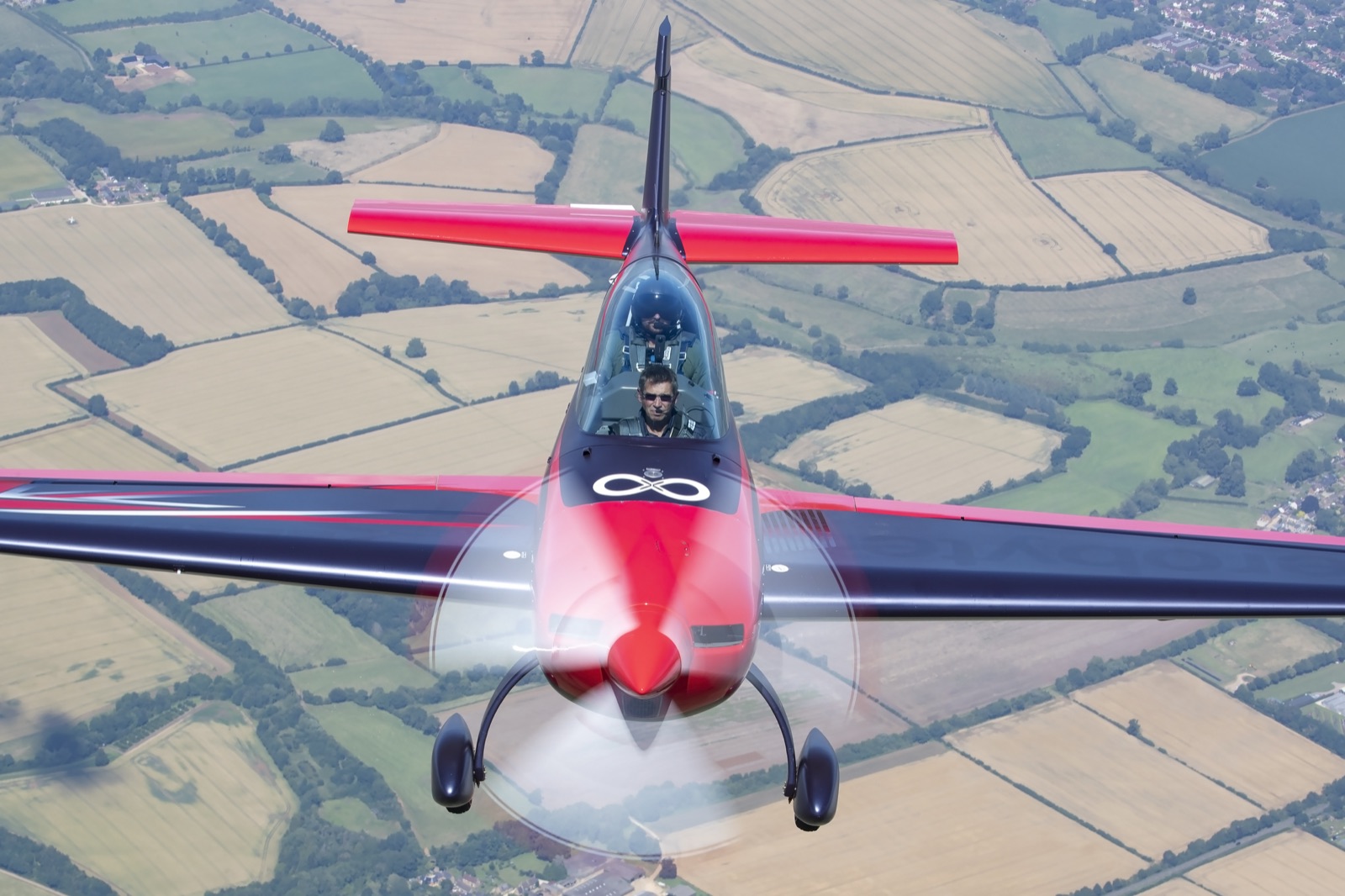 The Extra 300 pulling up hard over the fields