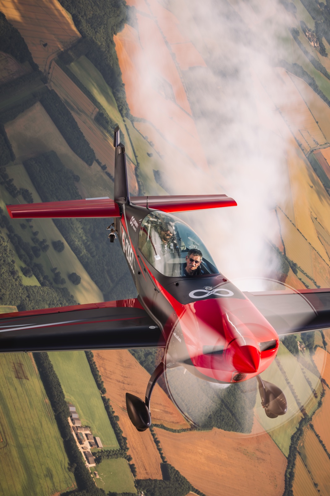 The Extra 300 flying up through its own smoke trail