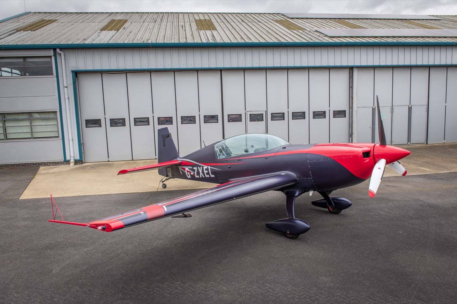 The Extra 300 seen from behind its own wing outside the hangar