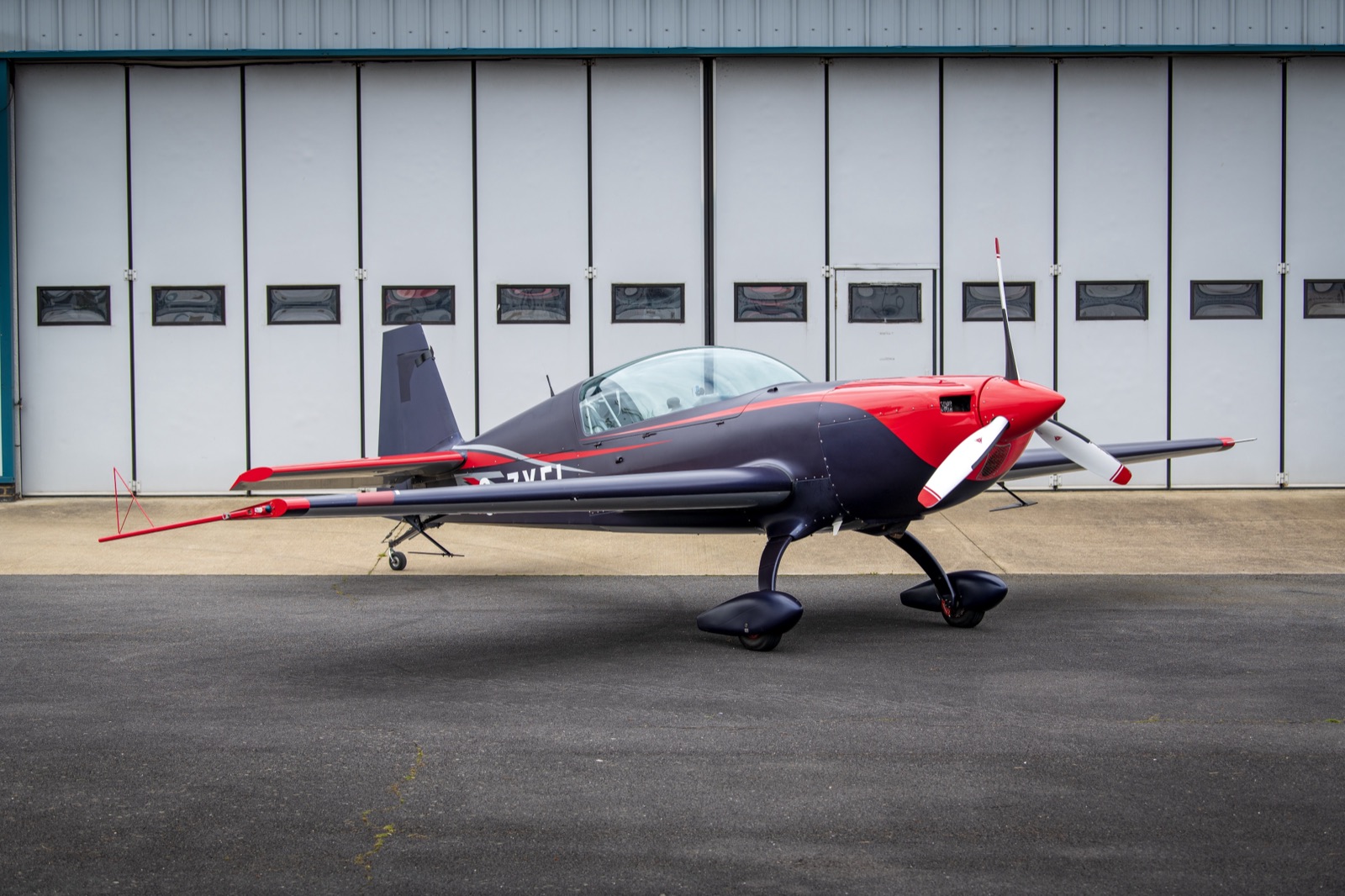 The Infinity Aerobatics Extra 300, G-ZXEL, parked in front of the hangar doors